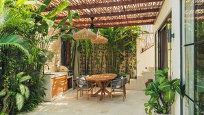 A poolside area with a table and chairs, surrounded by lush greenery and a pergola. - Villa Rasa Rasa by Alfred in Bali (Cemagi)