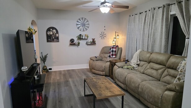 A living room with a sofa, armchair, coffee table, TV stand, and decorative items.