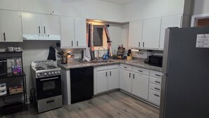 A modern kitchen with white cabinets, a stainless steel stove, a dishwasher, and a refrigerator with a WiFi sign.
