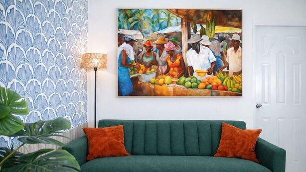 Un divano verde con cuscini arancioni, un quadro raffigurante una scena di mercato e una carta da parati decorata.