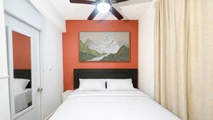Una camera da letto con un letto, una ventola a soffitto, un dipinto di montagne e una porta.