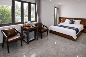 A hotel room with a bed, two chairs, a small table with items, a TV, and a view of a swimming pool. - Senna Garden HomeStay (Hoa Lu)