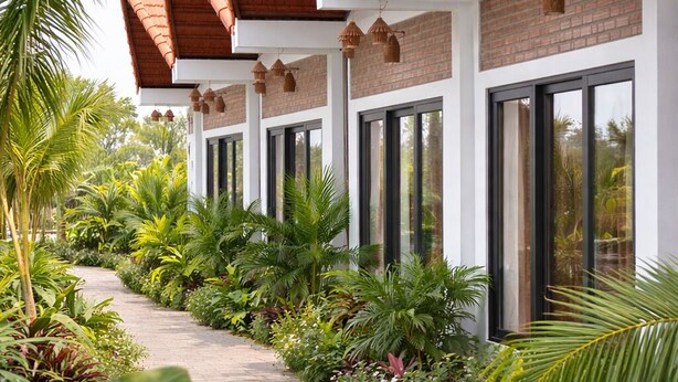 A row of modern buildings with terracotta roofs, large windows, and a pathway lined with tropical plants. - Senna Garden HomeStay (Hoa Lu)