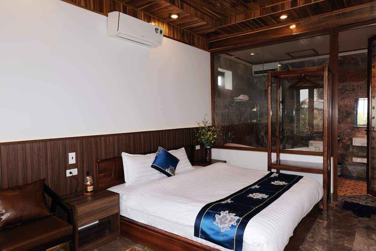 A bedroom with a large bed, wooden headboard, bedside table, and a nightstand.