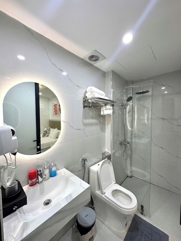 A modern bathroom with a white sink, toilet, and glass-enclosed shower.