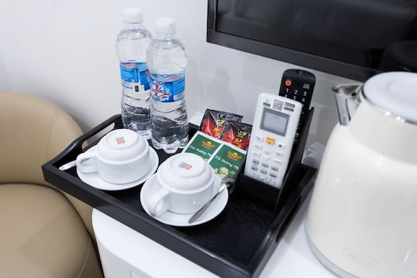 Una bandeja con un microondas, una tetera, dos botellas de agua, un teléfono móvil y algunos paquetes de comida.