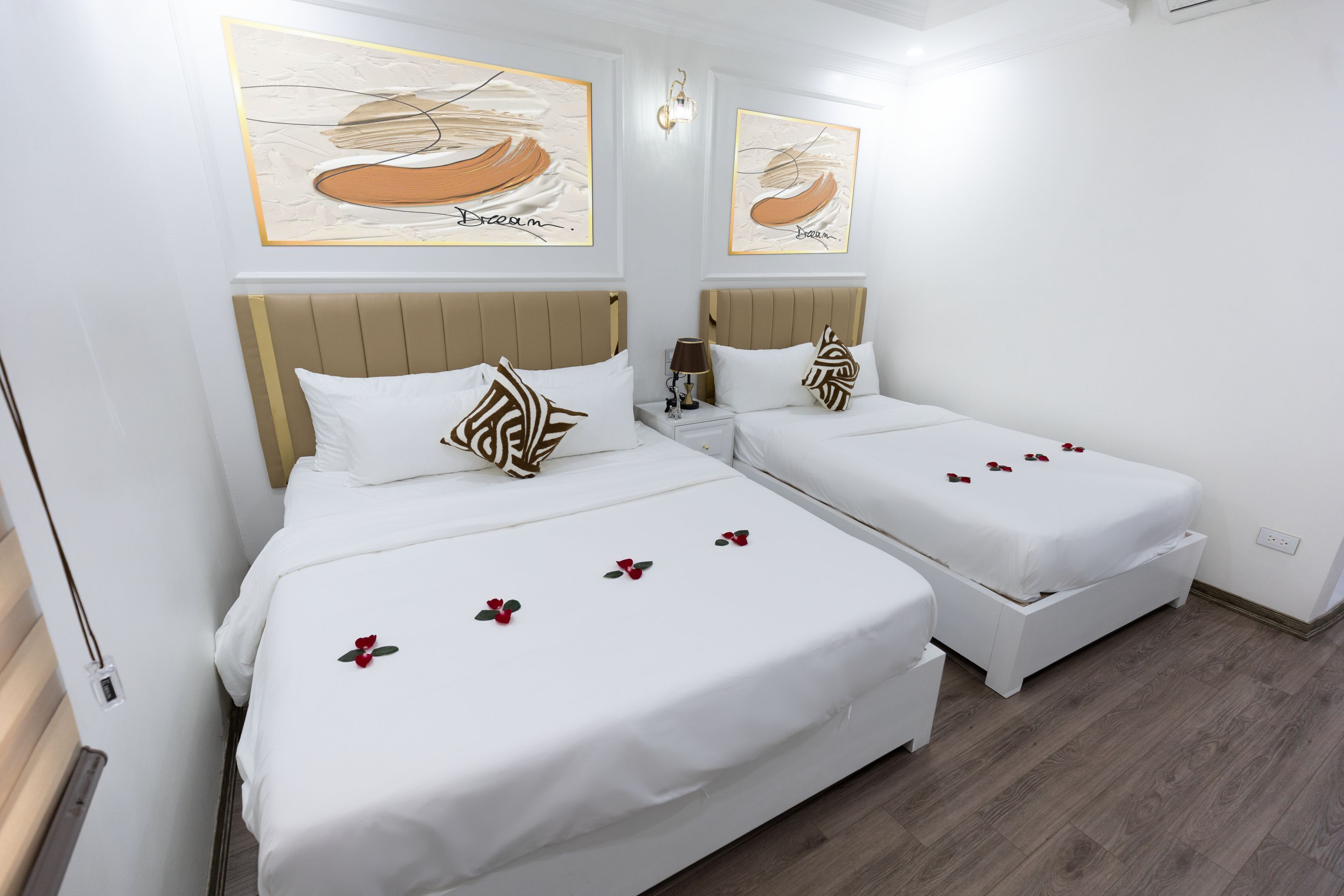 Une chambre d’hôtel avec deux lits, du linge de lit blanc et des œuvres d’art accrochées aux murs.