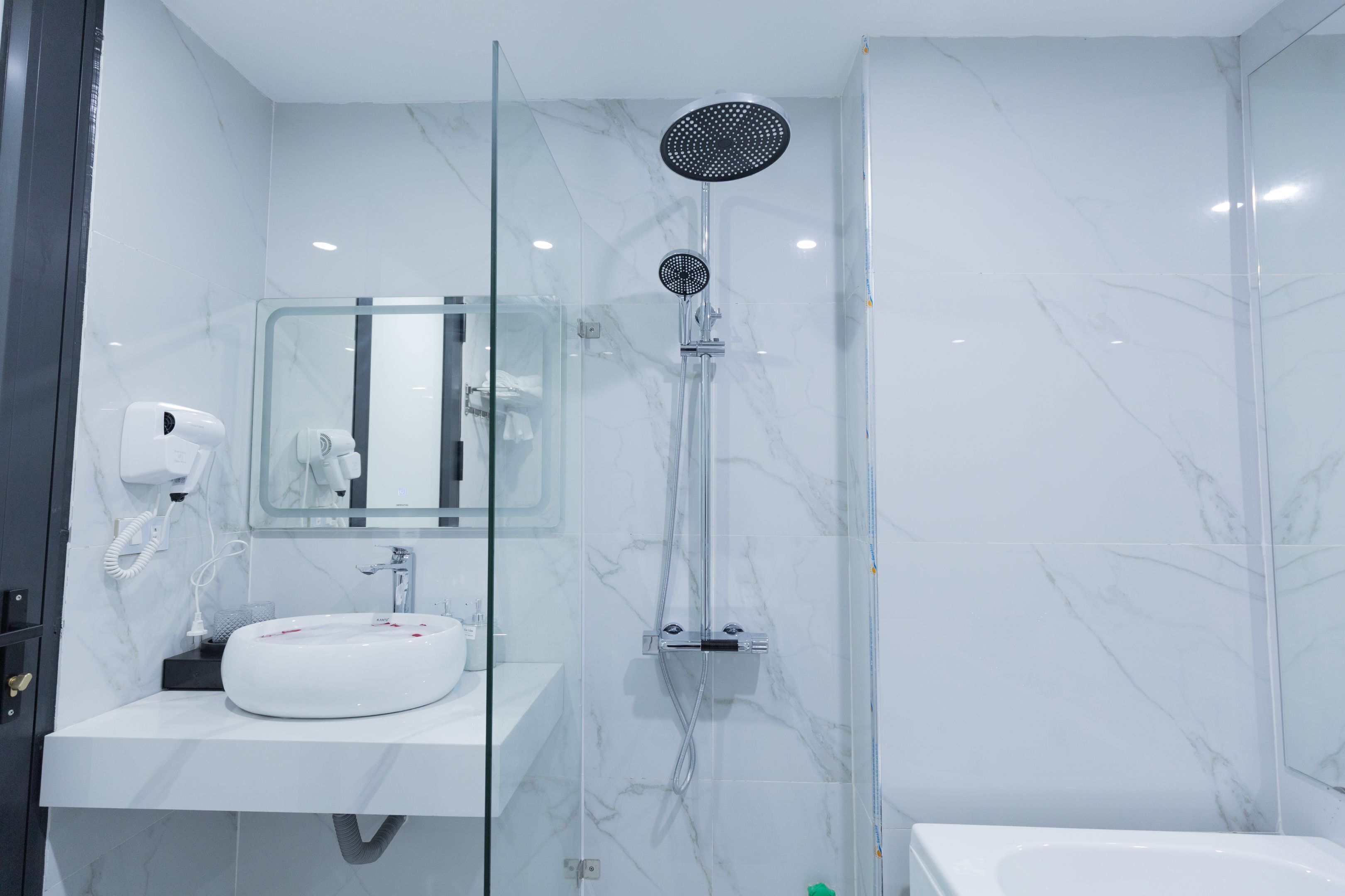 A modern bathroom with a glass-enclosed shower, a white sink, and a mirror above the sink.