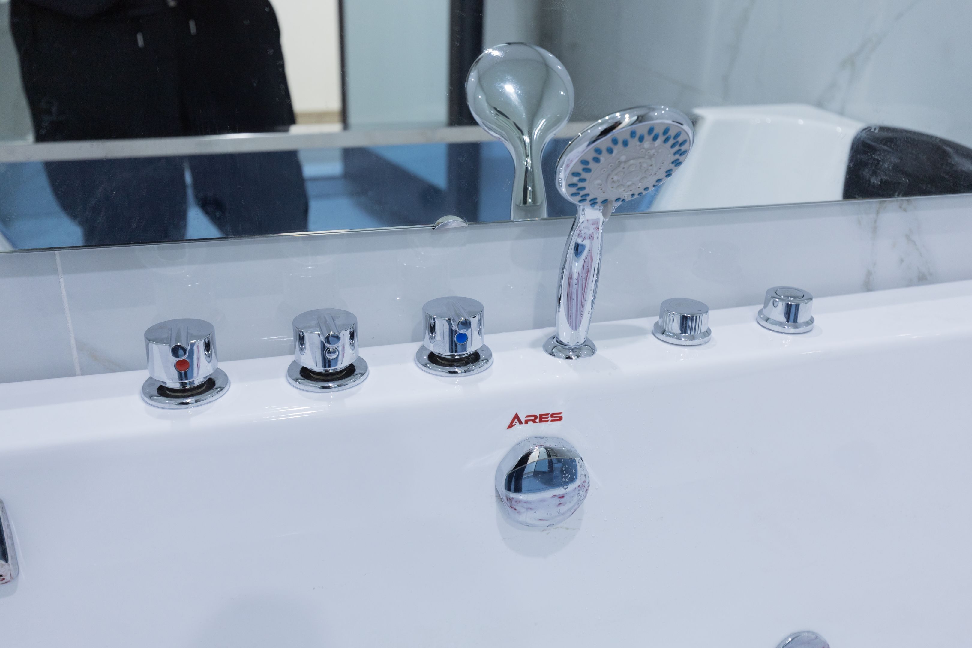 Baño con bañera blanca, espejo y accesorios de cromo.