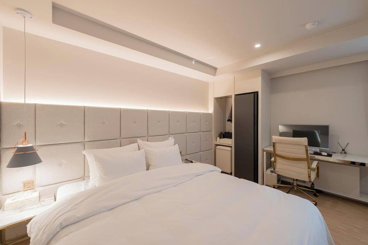 A modern hotel room with a large bed, a desk with a computer, and a TV.