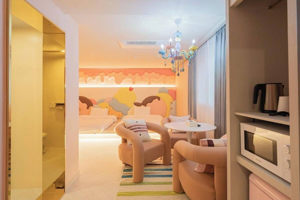 A modern hotel room with a sofa set, a small round table, a microwave, and a television.