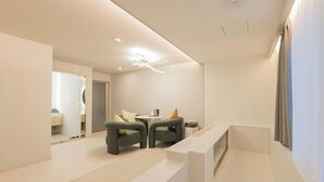 A modern hotel lobby with a reception desk, two armchairs, a small table, and a mirror. - Denbasta Hotel Busan Jeonggwan (Busan)