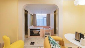 A hotel room with a bed, a small desk, a chair, a table with a kettle, and a window with curtains. - Denbasta Hotel Busan Jeonggwan (Busan)