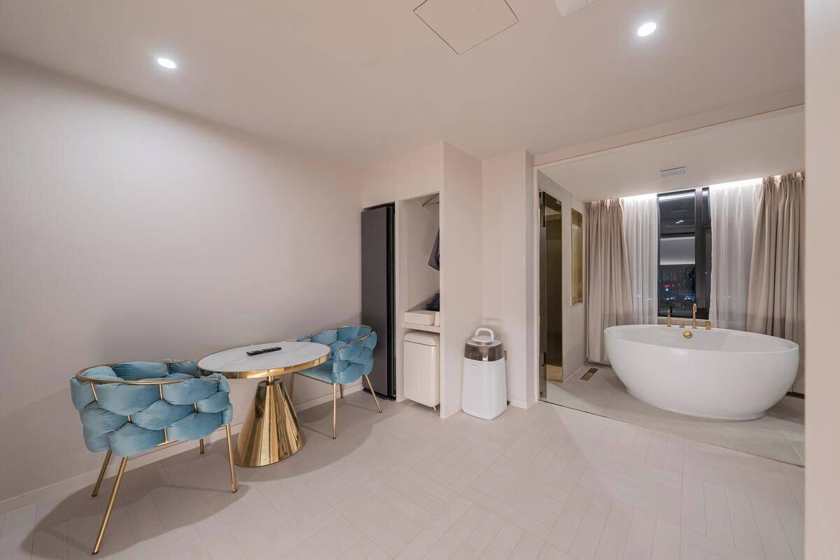 A modern bathroom with a freestanding bathtub, a vanity with a mirror, and a seating area with a round table and chairs.
