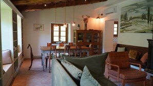 Un salon chaleureux avec un plafond en bois, un coin repas avec une table et des chaises en bois, et un tableau accroché au mur.
