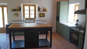 Une cuisine avec une table en bois, un fourneau et des placards.