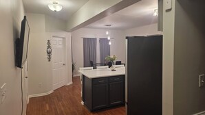 A modern kitchen with a black refrigerator, white cabinets, and a wooden floor. - 5-BR / King Beds / Massive Loft / Amazing Location / 10 mins to Downtown Raleigh (Knightdale)