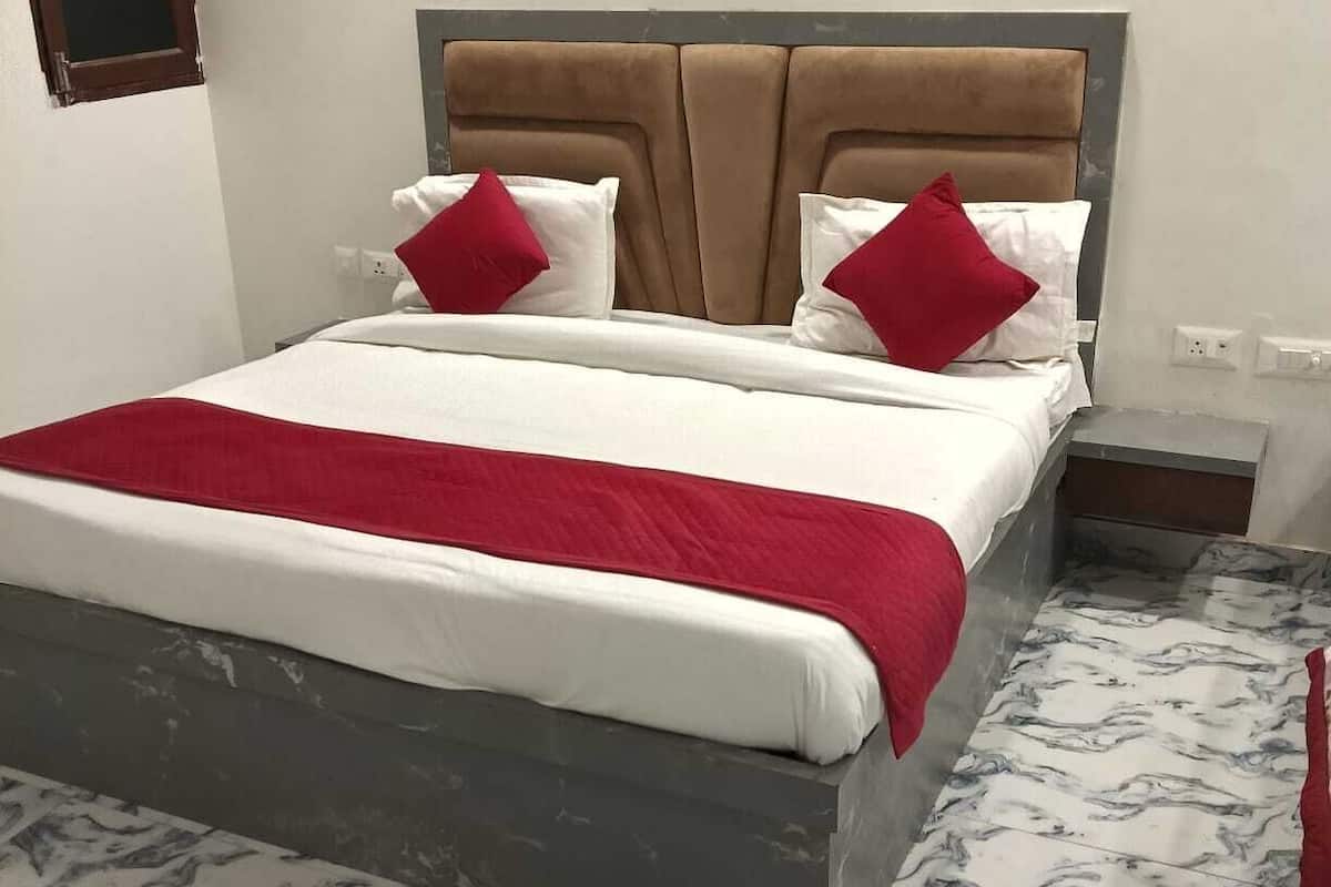 Un letto con una testiera, biancheria da letto bianca e cuscini rossi.