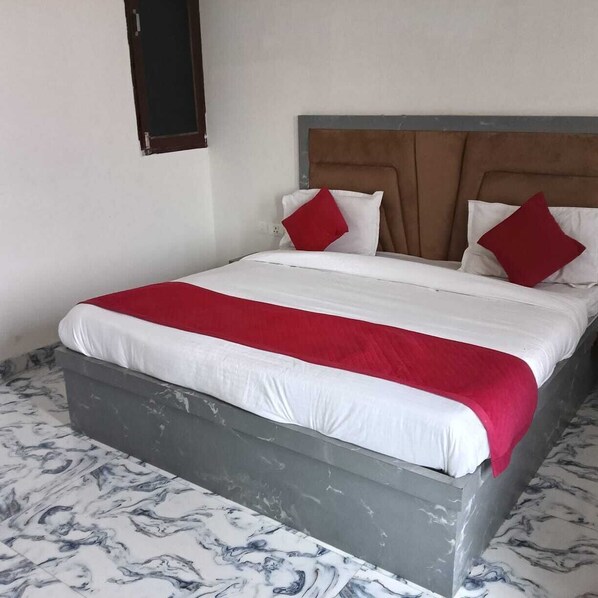 Un letto con una coperta bianca e rossa, una testiera grigia e un pavimento a motivi marmorizzati.
