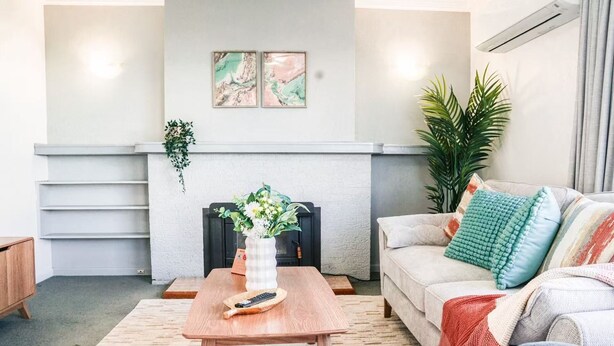 Een woonkamer met een open haard, een bank, een salontafel en een plant.