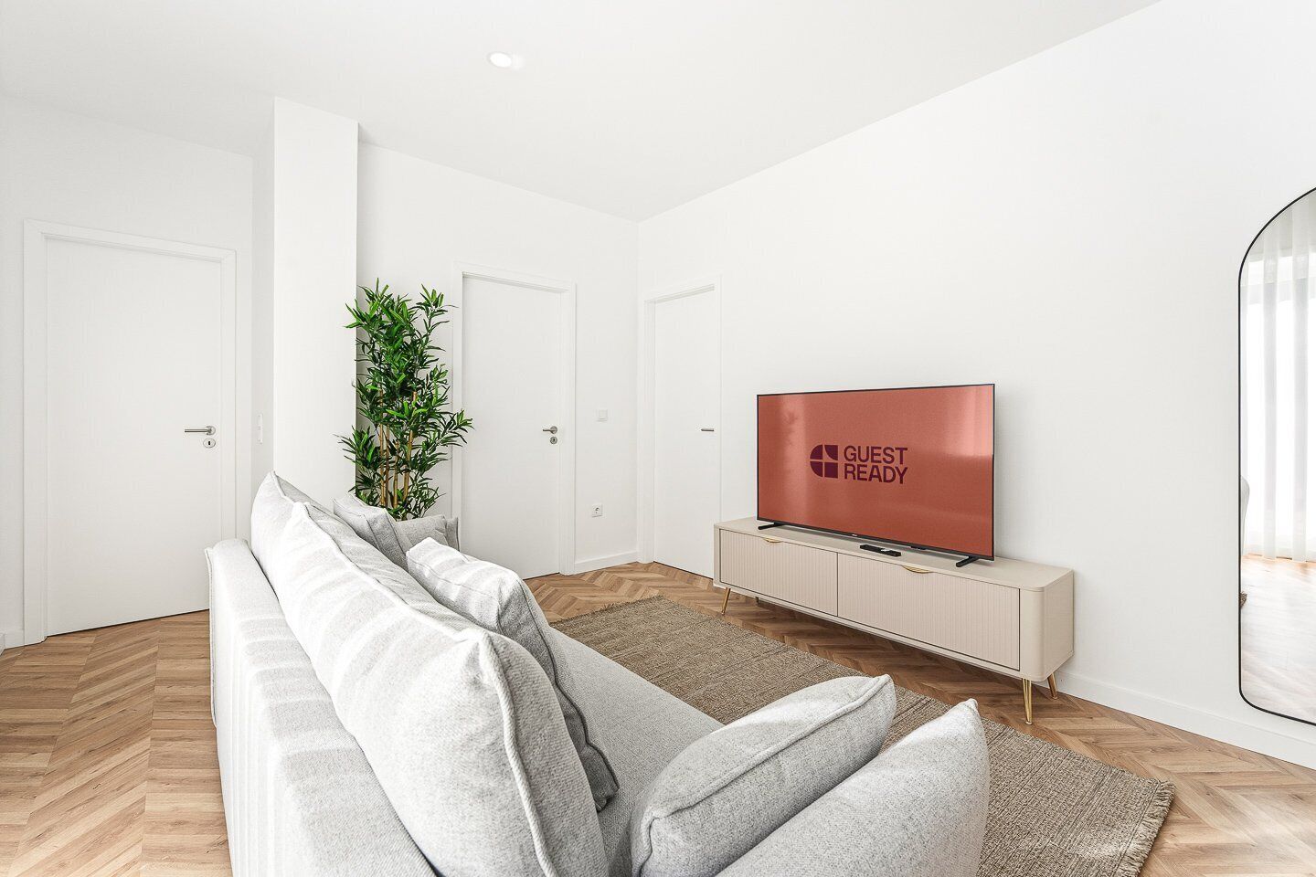 Ein modernes Wohnzimmer mit einer Couch, einem Fernseher, einer Pflanze und einem minimalistischen Design.