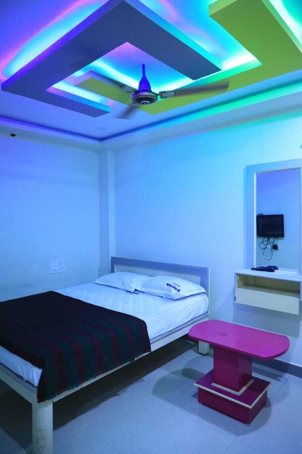 A bedroom with a bed, a bedside table, a mirror, and a ceiling fan.