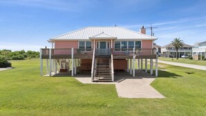 Una casa de dos pisos con un porche cubierto y una escalera que lleva al nivel superior.