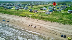 Vista aérea de una zona residencial costera con casas, una playa y una ubicación señalada.