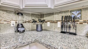 Eine Küche mit Granit Arbeitsplatten, einem Mixer, einem Messerblock und einer Spritzschutzleiste mit Mosaikfliesen.
