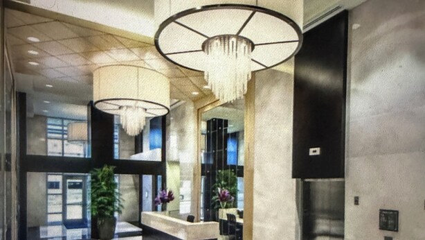 Una hall con reception, area salotto e un grande lampadario.