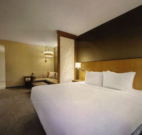 Une chambre d’hôtel avec un grand lit, une table de chevet, une lampe et une petite table avec une chaise.