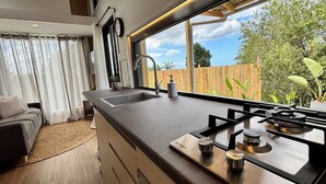Una cocina moderna con un amplio ventanal, un lavamanos integrado y una estufa a gas.