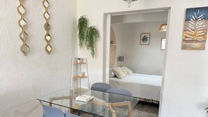 A modern room with a glass dining table, two chairs, a sofa, and a bed. - 100m from the beach - Cozy and with 24/7 security (Jacó)