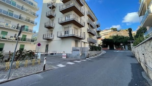Un edificio residenziale a più piani con balconi, cielo sereno e strada antistante.