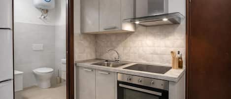 A modern kitchen with a built-in oven, stainless steel sink, and a range hood.