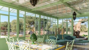 Ein Wintergarten mit Glasveranda, einem Esstisch mit Stühlen, einer Couch und einem dekorativen Globus.