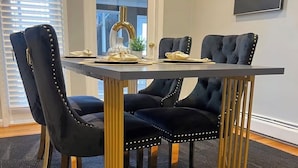 Een eettafel met vier stoelen, elk met een gouden frame en zwarte bekleding.