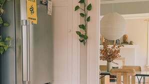 Une cuisine avec un réfrigérateur en acier inoxydable, une porte blanche et une plante suspendue.