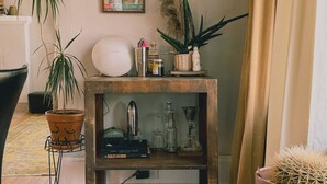 Un salon avec une table basse en bois, une plante en pot, un tableau encadré et un panneau accroché au mur.