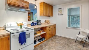 A kitchen with wooden cabinets, a white stove, and a window with a view. - Cozy 1-bedroom cottage in serene Fiddletown (Fiddletown)