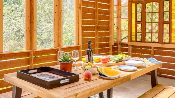 A wooden table with a tray, wine glasses, a bottle, and various fruits and vegetables. - Cozy 1-bedroom cottage in serene Fiddletown (Fiddletown)