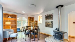 A modern living room with a dining area, a fireplace, and wooden shelving. - Cozy 1-bedroom cottage in serene Fiddletown (Fiddletown)