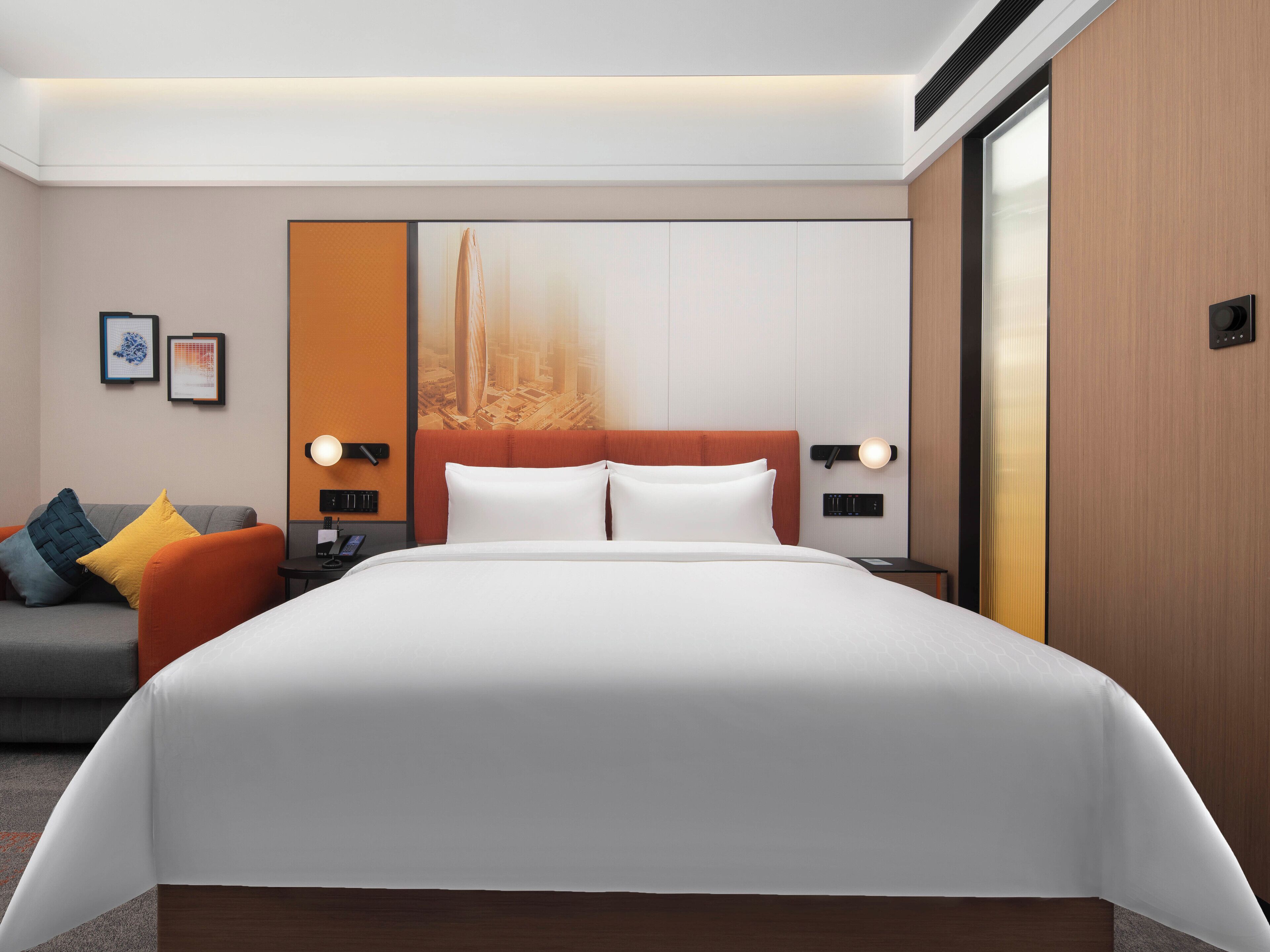 Una habitación de hotel moderna con una cama grande, un sofá y una obra de arte con vistas a la ciudad.