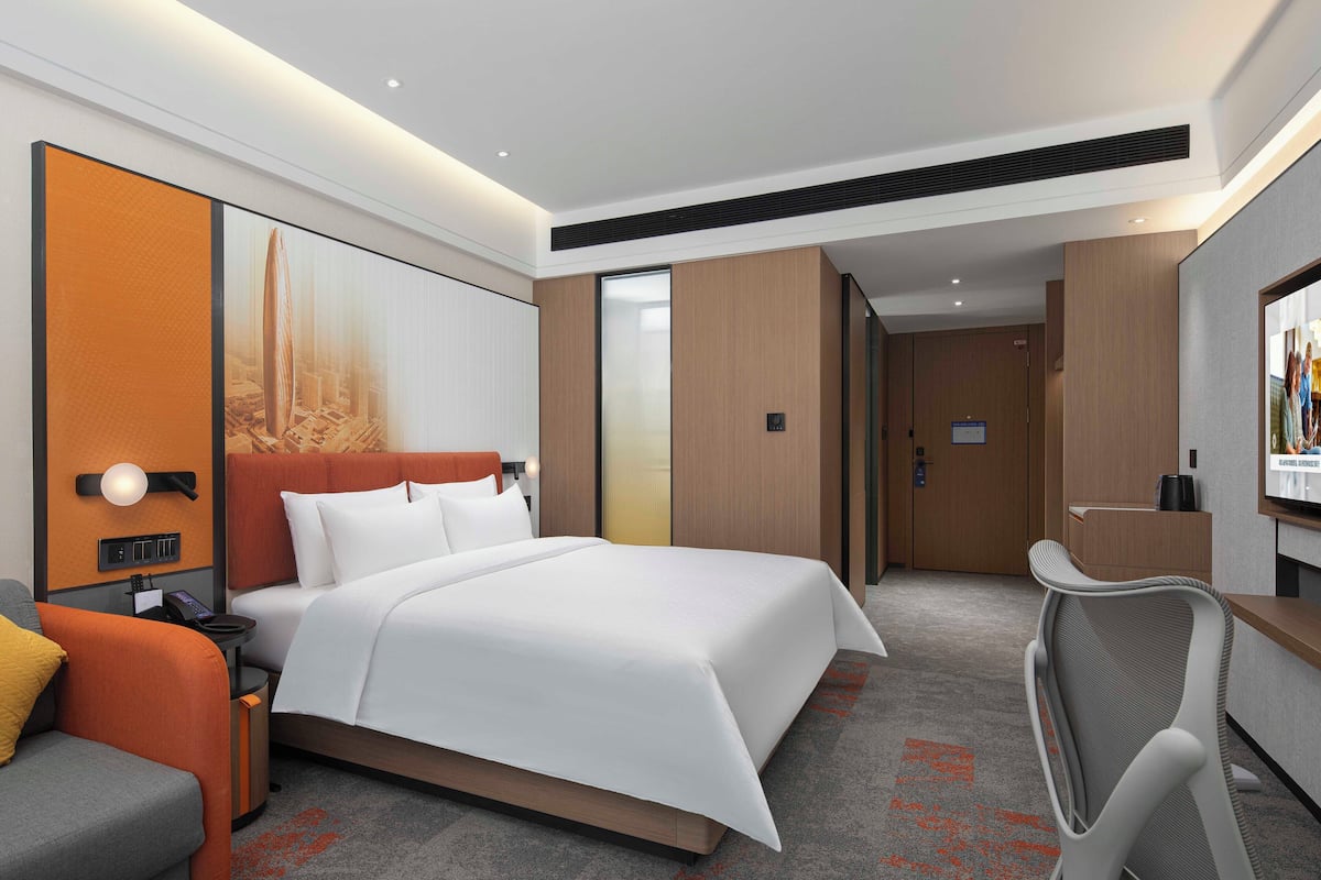 Een moderne hotelkamer met een groot bed, een bureau, een stoel en een televisie.