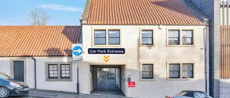 En byggnad med en infart till en parkeringsplats, en skylt som visar enkelriktad trafik och en skylt som förbjuder parkering.