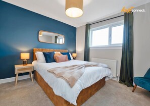 Une chambre à coucher avec un grand lit, une table de chevet, un miroir et une fenêtre avec des rideaux.