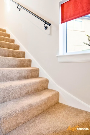 A carpeted staircase with a handrail and a window with a red blind. - 3Bed House I Sleeps 6 I Dunfermline (Dunfermline)