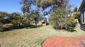 A backyard with a brick patio, a brick barbecue, and various trees. - Lookin Good is a short walk to Inyadda Beach (Manyana)