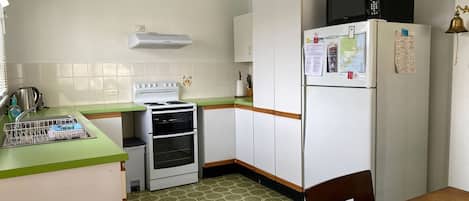 A compact kitchen with a stove, oven, microwave, and refrigerator.