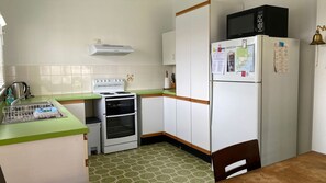A compact kitchen with a stove, oven, microwave, and refrigerator. - Lookin Good is a short walk to Inyadda Beach (Manyana)